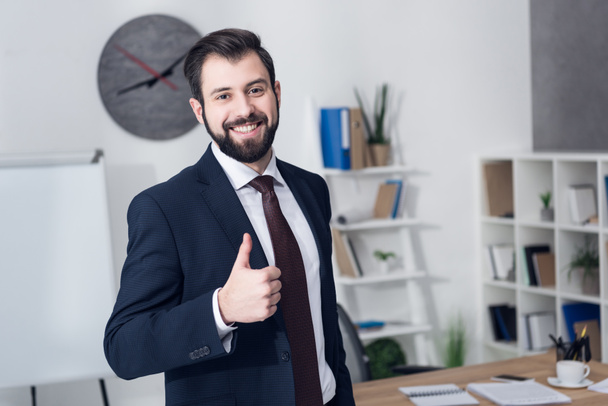 портрет улыбающегося бизнесмена, показывающего большой палец в офисе
  - Фото, изображение
