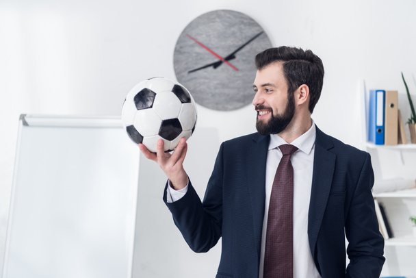 portrait of smiling businessman holding soccer ball in office - Fotoğraf, Görsel