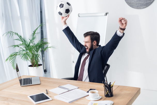 uomo d'affari eccitato in completo con pallone da calcio sul posto di lavoro in ufficio
 - Foto, immagini