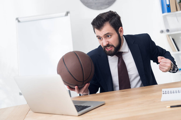 hombre de negocios enojado con pelota de baloncesto en el lugar de trabajo en la oficina
 - Foto, Imagen