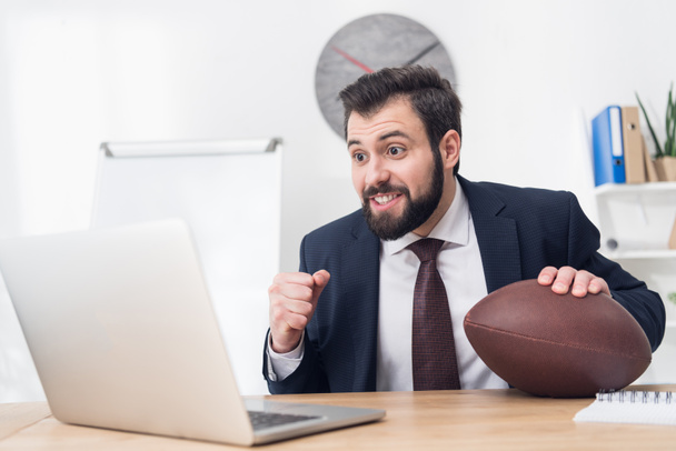 portret biznesmen z rugby piłka w miejscu pracy z laptopem w biurze - Zdjęcie, obraz