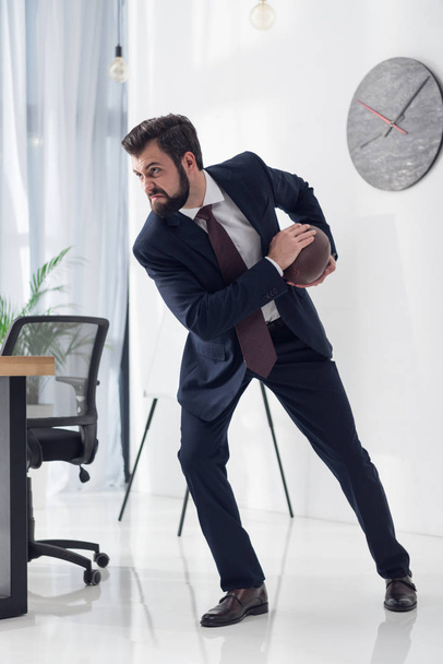 visão lateral de empresário irritado em terno jogando rugby no escritório
 - Foto, Imagem