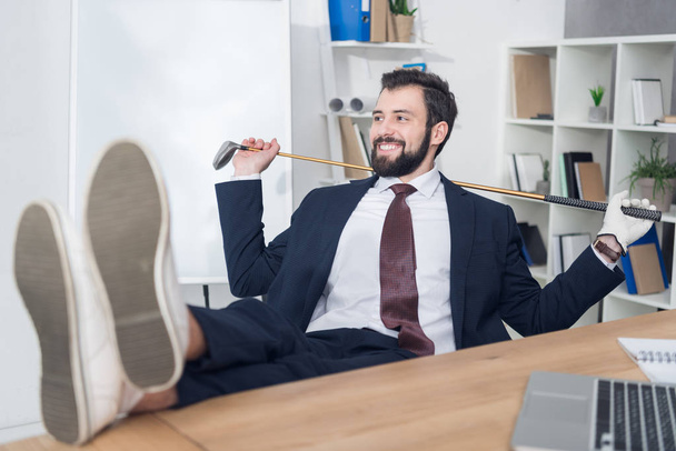 smiling businessman with golf equipment at workplace in office - Foto, immagini
