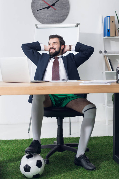 hombre de negocios feliz con pelota de fútbol descansando en el lugar de trabajo en la oficina
 - Foto, imagen