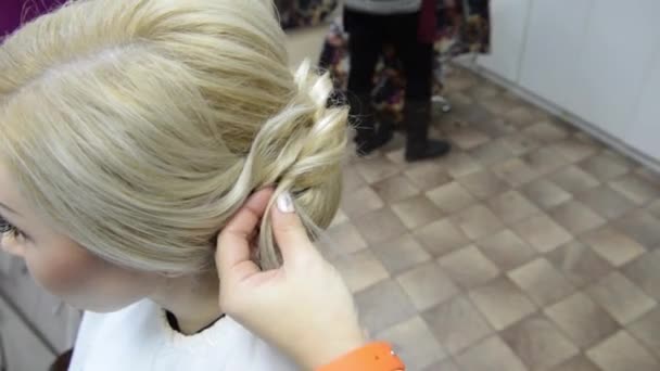 Hairdresser makes evening hairstyle close-up on blond hair of business woman in beauty salon - Footage, Video