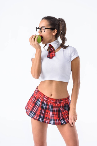 若いセクシーな女子高生は要するに赤い格子縞のスカート食用リンゴは白で隔離 - 写真・画像