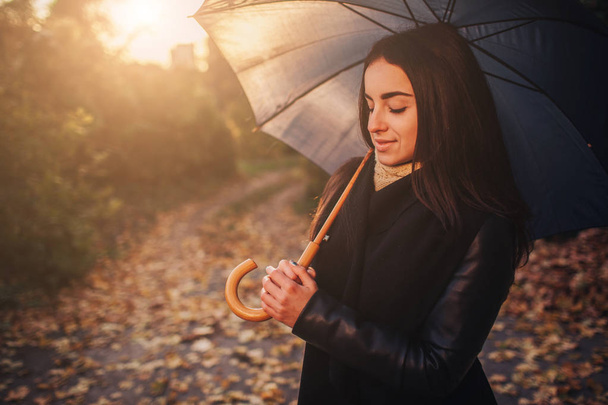 Autumn woman in autumn park with black umbrella. - 写真・画像