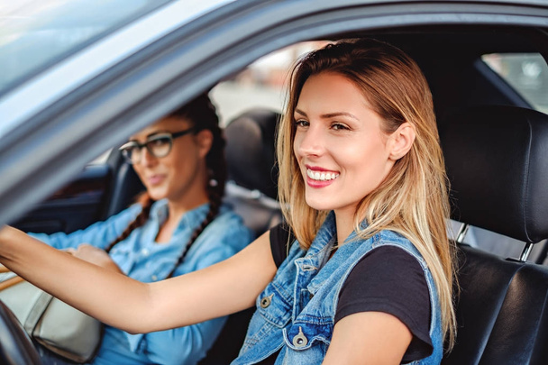 Kaksi tyttöystävää ajaa autolla ja hymyilee
 - Valokuva, kuva