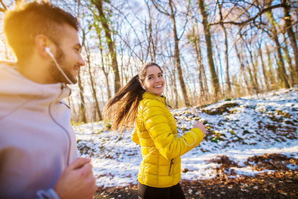 冬のスポーツ ウエア、屋外で幸せな笑みを浮かべてスポーティな若いカップル ジョギング トレーニング - 写真・画像