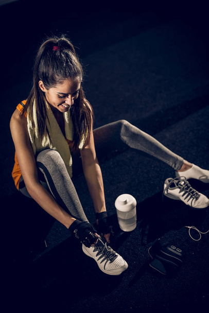 woman tying up shoelaces in gym - Photo, image