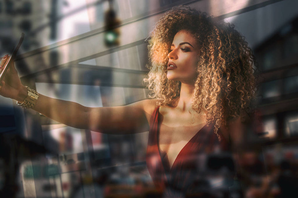 Double exposure of beautiful woman portrait taking selfie and blurred cityscape - 写真・画像