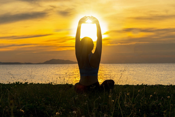 瞑想ヨガのライフ スタイル女性海の夕日にシルエットが重要なリラックスしてください。健康の概念 - 写真・画像