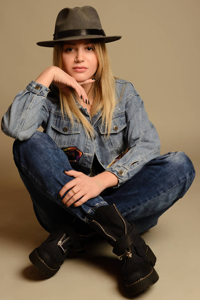 Chica en jeans, botas, sombrero y chaqueta sentado
 - Foto, imagen