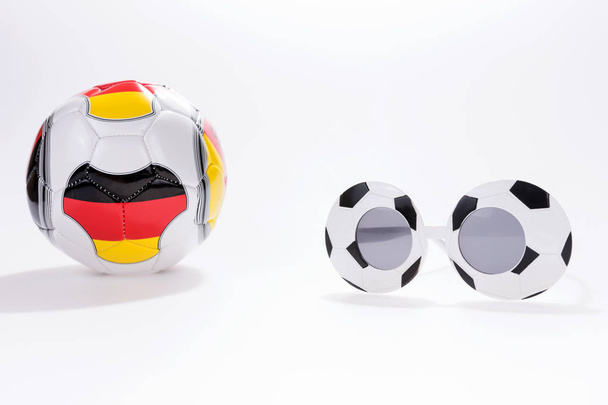 Fußballsportbrille und Fußball mit Deutschland-Fahne auf weißem Hintergrund - Foto, Bild