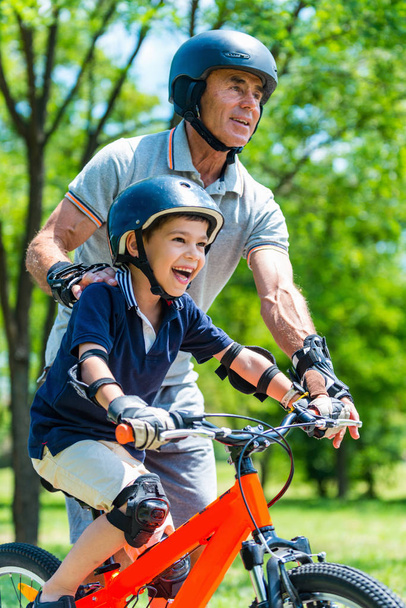 Dziadek i wnuczek, zabawy w parku. Rolki na rolkach i rowerze - Zdjęcie, obraz