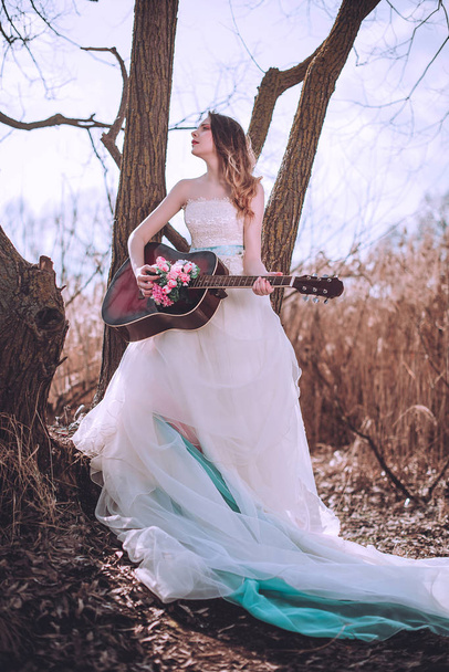 Beautiful romantic european girl with guitar with flowers inside, posing outdoors. Concept of music and nature. Spring time. - Fotoğraf, Görsel