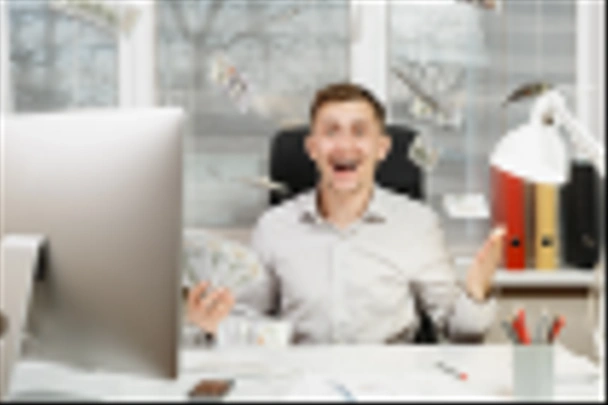 Szczęśliwy uśmiechający się działalności człowieka w koszuli siedzi przy biurku z dużo gotówki, pracujący komputer z monitorem nowoczesne, dokumenty w biurze światła na tle okna. Menedżera lub pracownik zwycięzca. - Zdjęcie, obraz