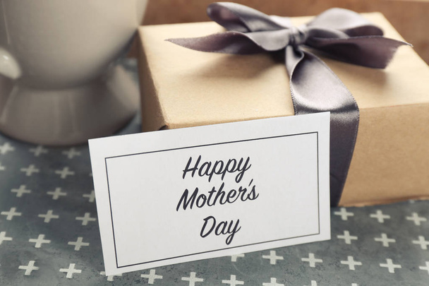 Card with words "Happy Mother's day" and gift box on table - 写真・画像