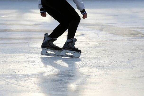 voeten op de schaatsen van een persoon rollend op de ijsbaan - Foto, afbeelding