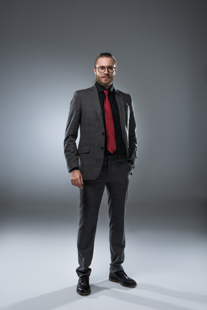 Seruous businessman in glasses in formal suit looking at camera, isolated on gray  - Foto, Imagen