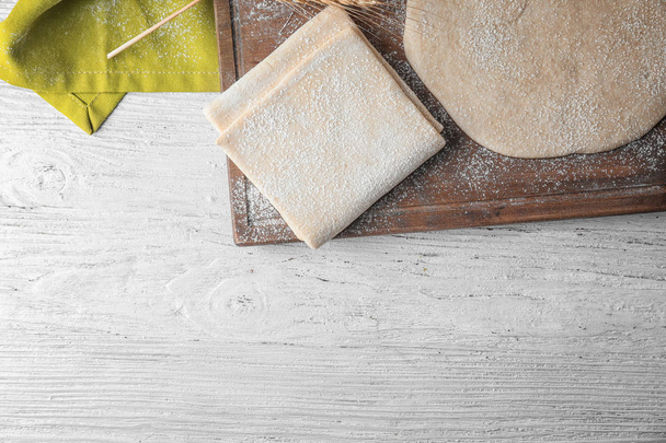 Wooden board with raw flaky dough  - Фото, зображення