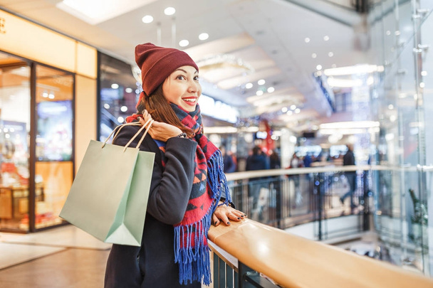 Krásná mladá žena nakupování oblečení s taškami v obchoďáku během vánoční prodej. - Fotografie, Obrázek