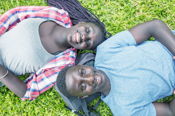 リラックスできる草按アフロ アメリカのティーンエー ジャーのカップルと  - 写真・画像