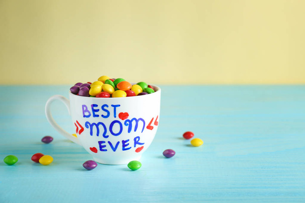 Cup with text BEST MOM EVER and candies  for Mother's day on table - Foto, Imagem