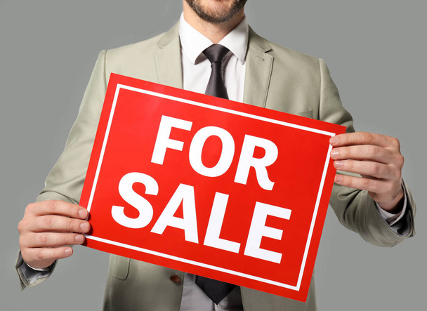 Real estate agent holding "For sale" sign  - 写真・画像