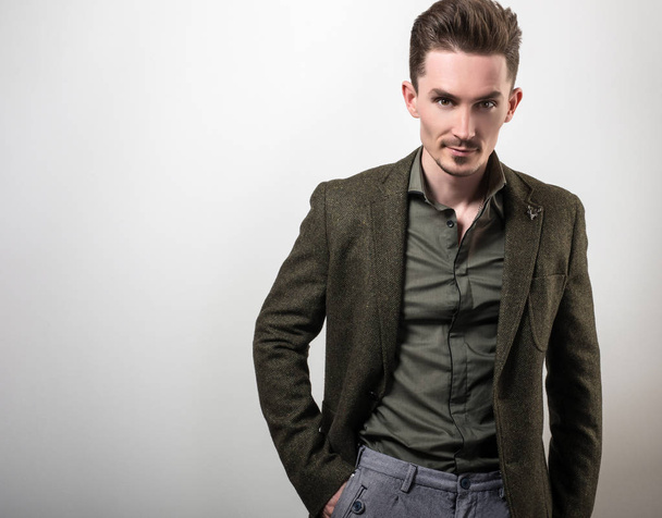 Handsome young elegant man in dark green jacket pose against gray studio background. - Fotografie, Obrázek