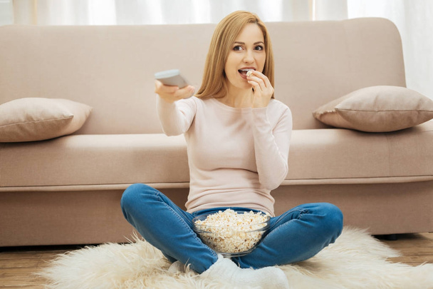 Lovely woman eating popcorn on the floor - Photo, Image