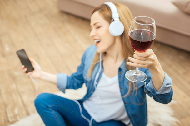 Joyful woman singing to music and drinking wine - Fotografie, Obrázek