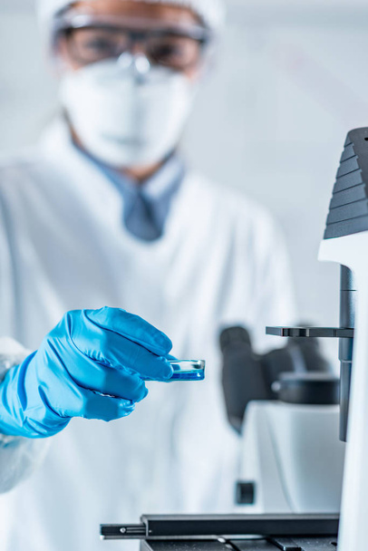 Recherche en laboratoire de biotechnologie, Technicien plaçant la boîte de Pétri avec culture cellulaire au microscope
 - Photo, image