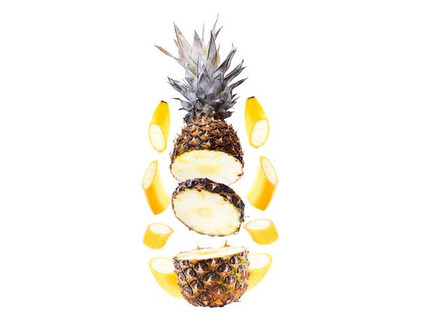 Pieces of banana and Pineapple in flight on a white background, isolated. Cut sliced into pieces fruit flying in the air - Photo, Image