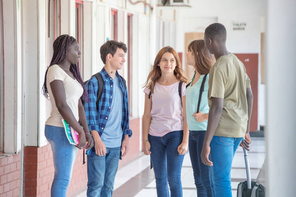 Мультиэтнические подростки одноклассники счастливы говорить в школьном дворе
 - Фото, изображение