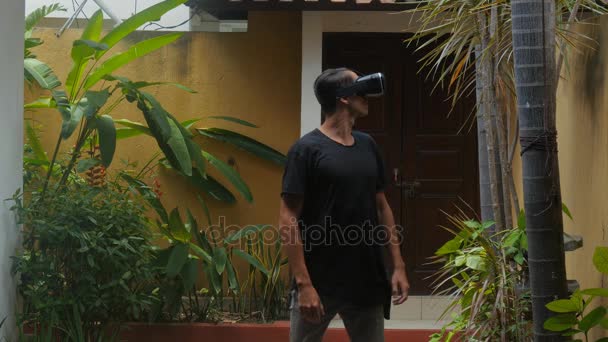Nuori mies käyttää virtuaalitodellisuus lasit kotipihalla
 - Materiaali, video