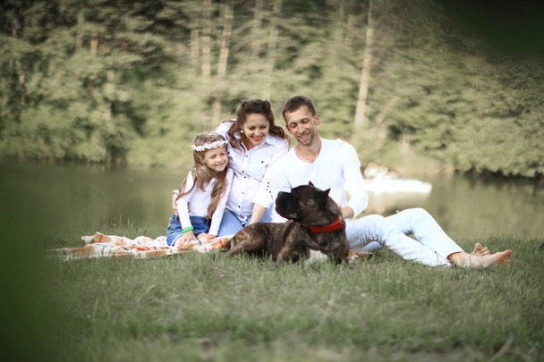 happy family with pet dog at picnic in a Sunny summer day. - Valokuva, kuva
