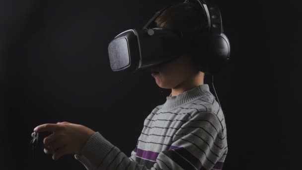 Boy uses VR-headset display with headphones and joystick for virtual reality game. UHD 4K - Footage, Video