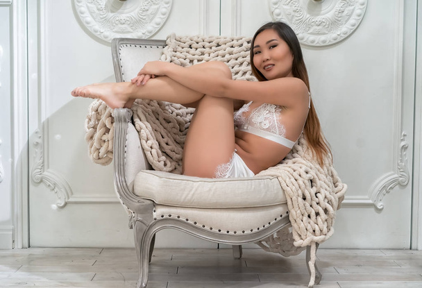 Beautiful alluring young asian woman in sexy white lingerie sitting in luxury armchair  - Fotografie, Obrázek