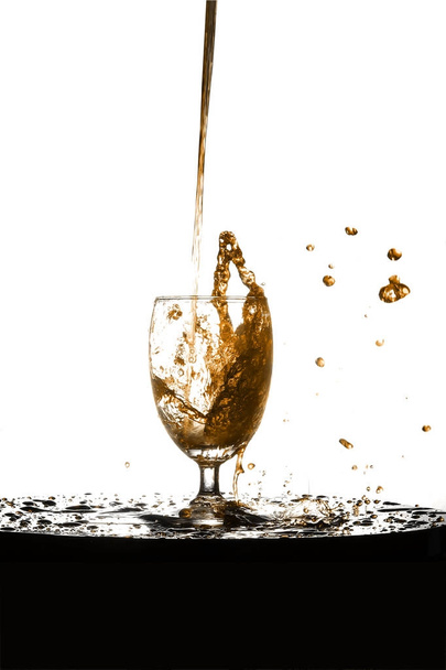 Pouring the amber liqueur into a glass of booze. - Photo, Image