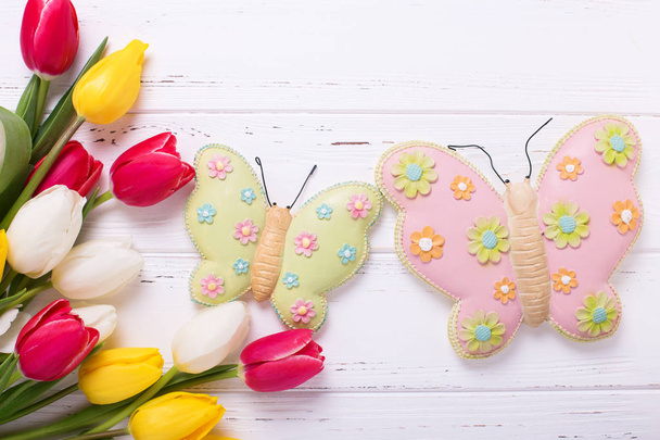 Bright yellow, pink  and white tulips flowers  and decorative butterflies on  vintage wooden background. Selective focus.  - Photo, image