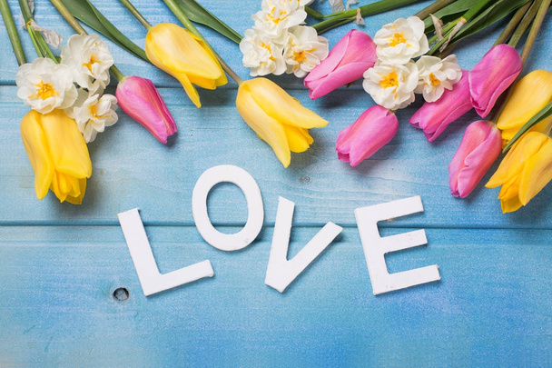 Word love and  pink, yellow and white flowers on blue wooden background. Love concept. Selective focus.  - Foto, immagini