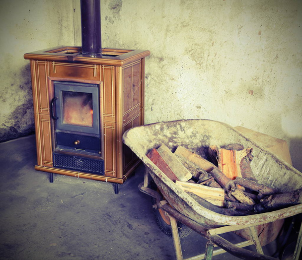 cserépkályha és a talicska teljes tűzifa, vintage hatású - Fotó, kép