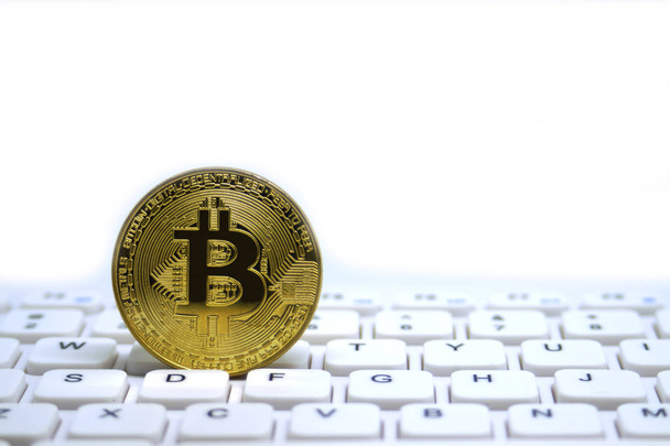 Golden symbolic coin of bitcoin on white keyboard. - Photo, Image