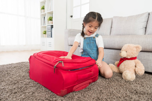 attractive little girl closing luggage suitcase - Fotó, kép