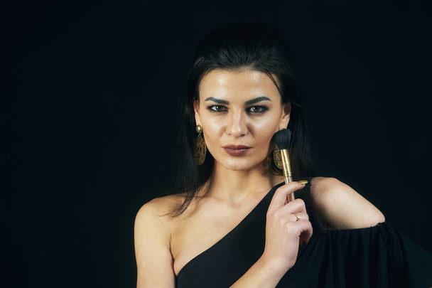 Portrait of beautiful young woman applying brush for makeup to the face .Cosmetic makeup. - Foto, Imagen