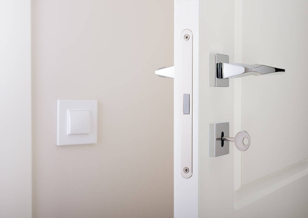 Closeup of white interior doors. Lock with key and chrome door handle - Fotografie, Obrázek