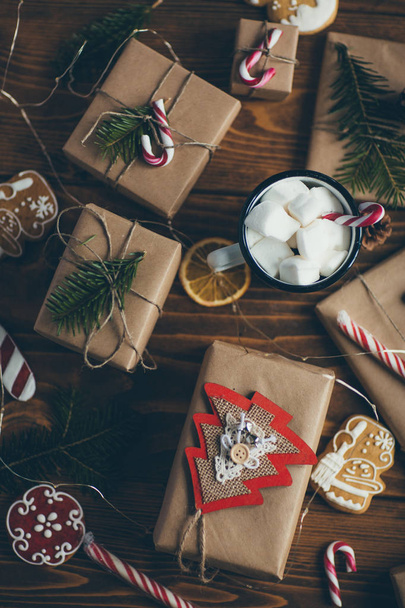 Cup of hot chocolate with marshmallows on wooden table with Christmas gifts - Фото, зображення
