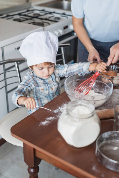 mother and adorable little child preparing dough at kitchen - Foto, Imagen