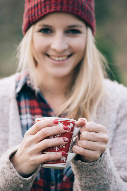 Une femme qui boit une boisson chaude. Fille avec des ongles rouges tenant une tasse chaude de café ou de thé à l'extérieur
. - Photo, image